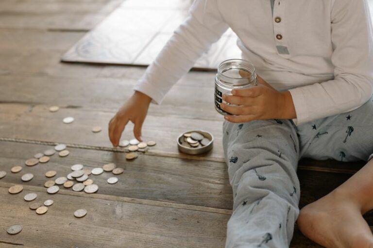 Child saving coins in a glass jar representing savings goals