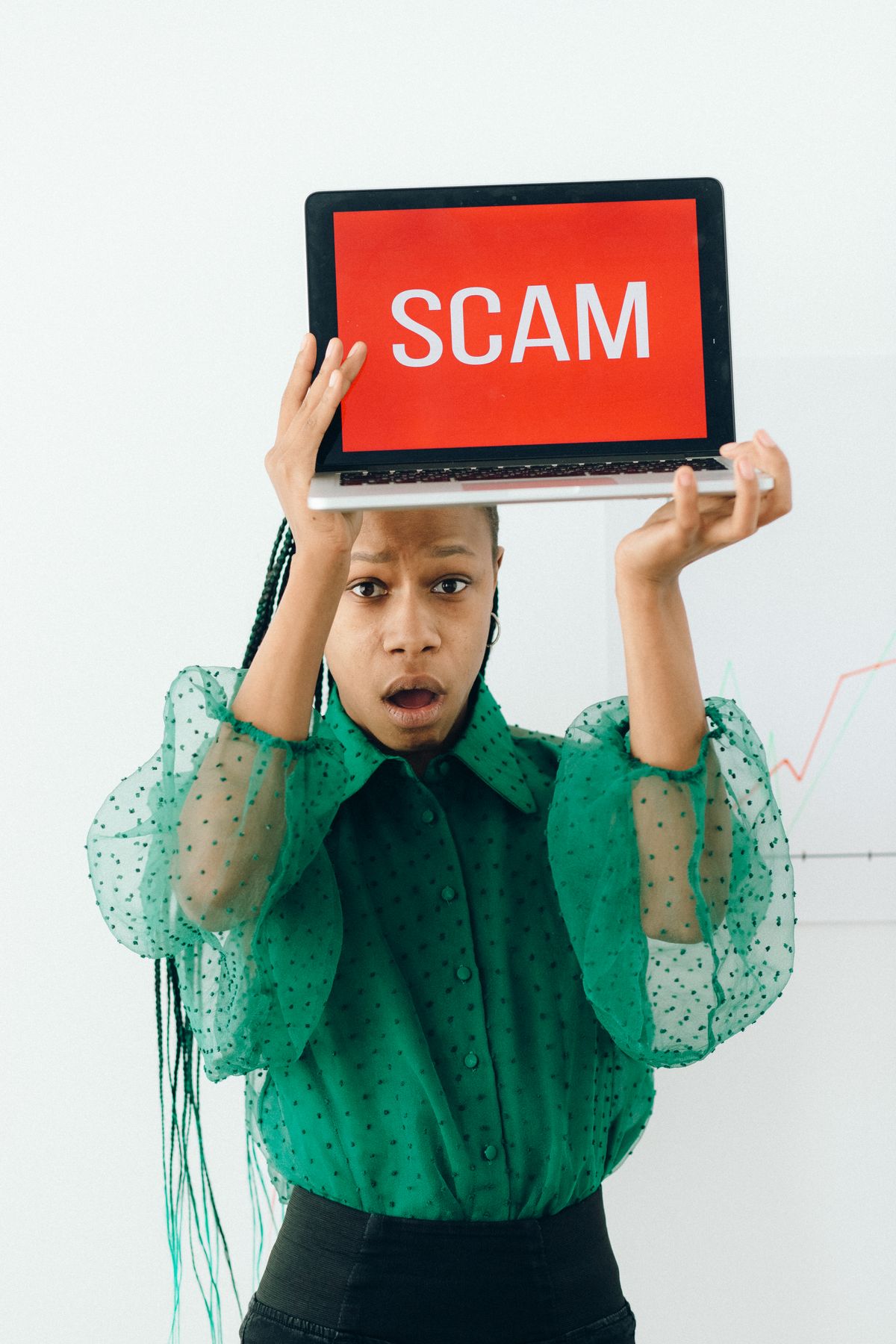 Businesswoman holding laptop showing a warning or scam alert, representing financial fraud awareness
