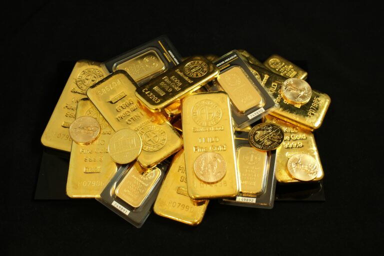 Gold bars and coins on a black surface symbolizing investment and wealth