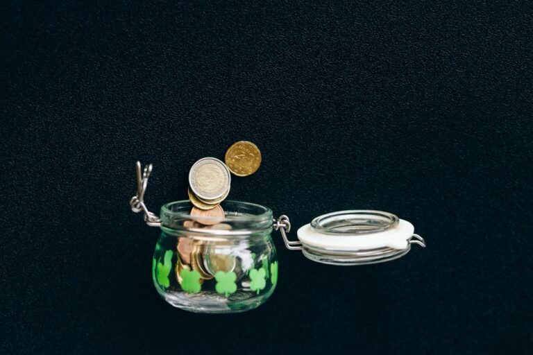 Glass jar with coins falling into it, symbolizing emergency fund savings