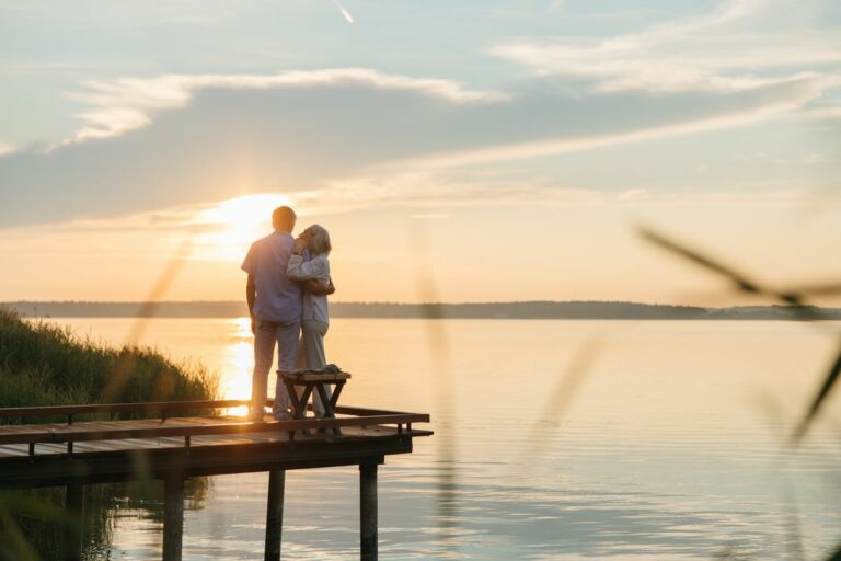 Senior couple embracing on a wooden dock at sunset, symbolising a comfortable retirement